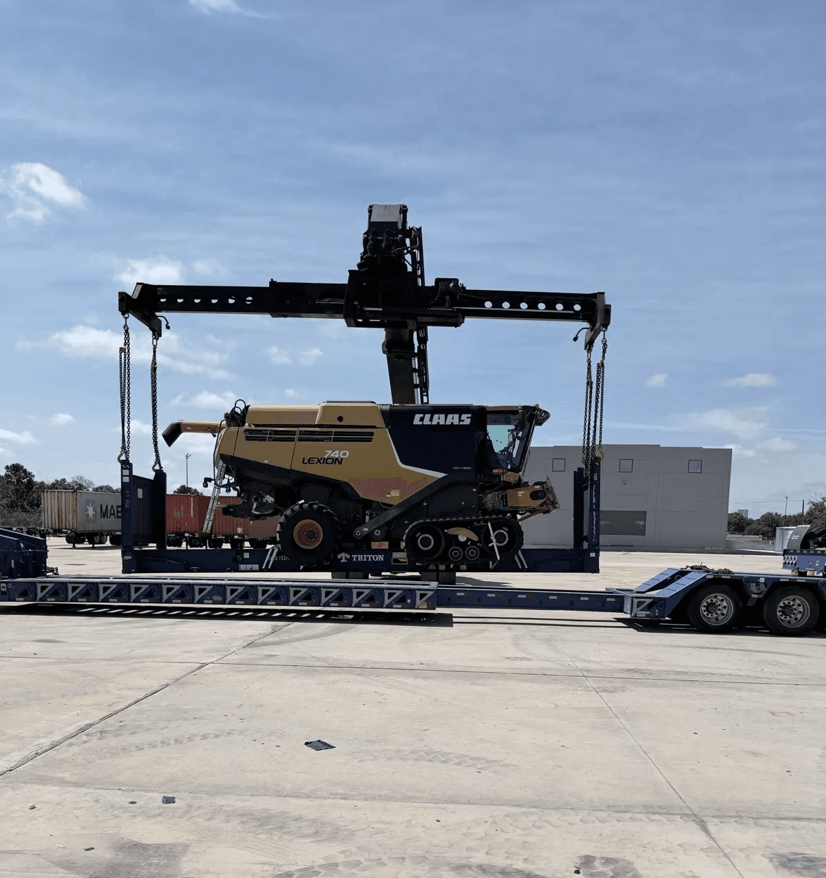 Harvester rigged on chains and swung into position over the flat-rack container
